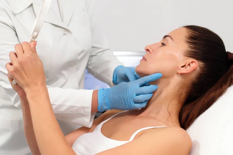 Une Dermatologue parle à une patiente assise sur une table de soins confortable. Le Dermatologue consultant conseille le soin d'hydrolevage du visage. Expertise Professionnelle. Cabinet du Docteur Dominique DENJEAN à PARIS 2